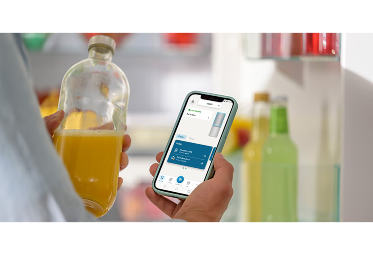 Απεικονίζεται χρήστης να χρησιμοποιεί την εφαρμογή στο κινητό, κρατώντας ένα μπουκάλι χυμό.